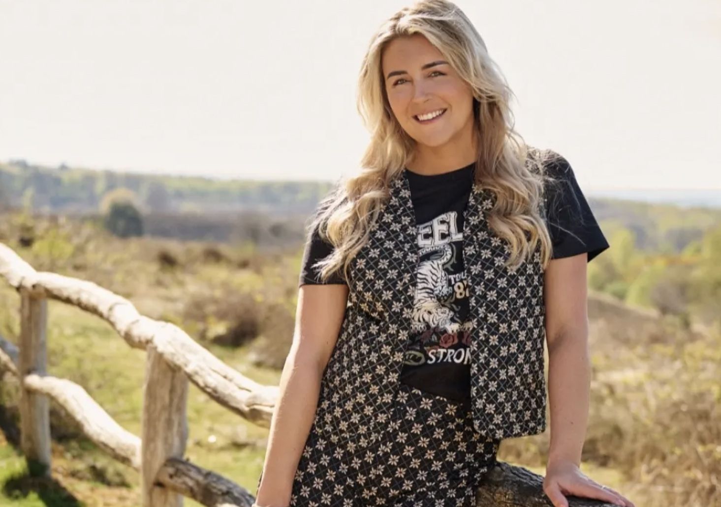 Lachend model bij een houten hek in de natuur